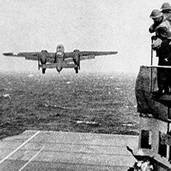 Witnessing a first. Anxious crew members watch as a plane never intended to be launched from a carrier struggles into the sky.